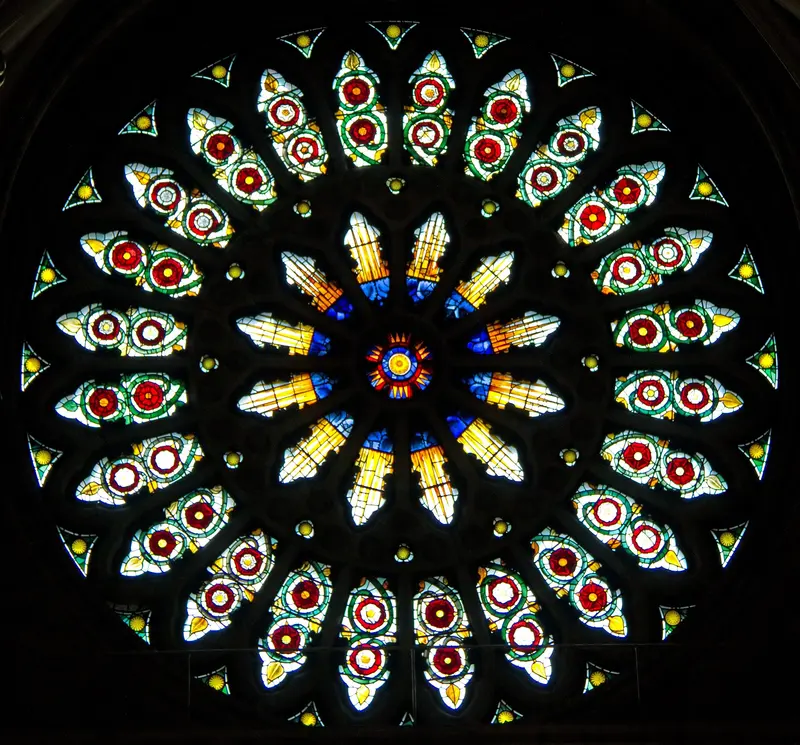 The circular rose window of York Minster, its petals of red, white and gold glass set in dark stone tracery